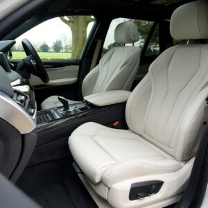 A close-up view of the clean, light-colored leather interior, focusing on the driver and front passenger seats of an SUV or modern car.