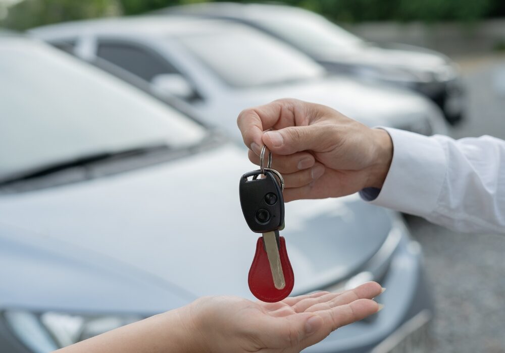 man handing keys to rental car to a woman